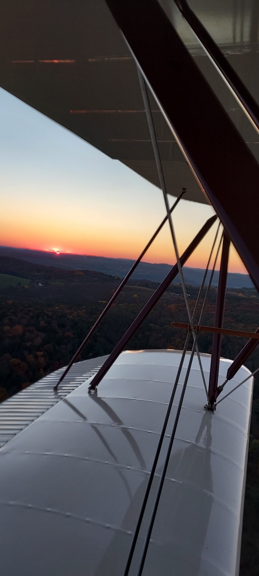Sunset view from biplane cockpit over autumn hills