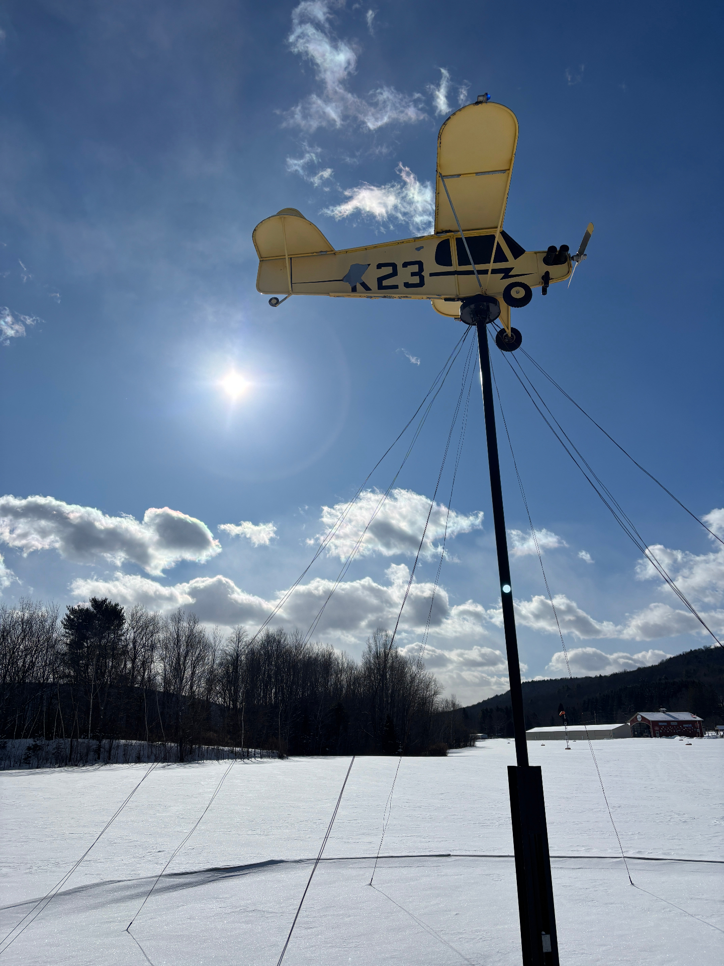 K23 airplane weathervane against winter sky with sun halo