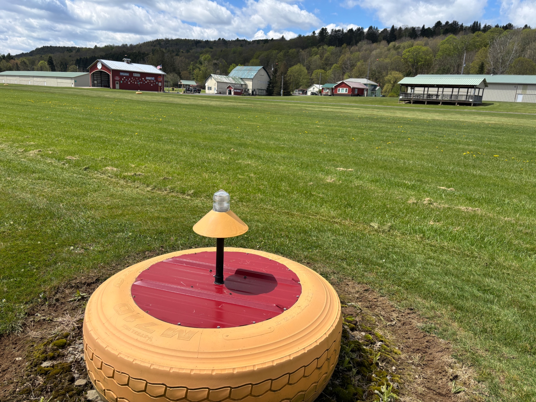 Runway edge light marker with hangars in background on a spring day