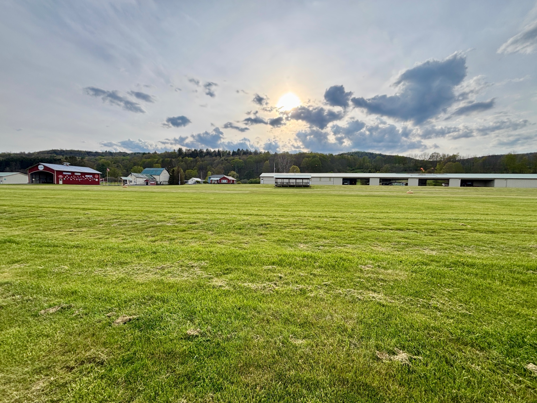 Wide view of airfield with red hangar and hangars under evening clouds