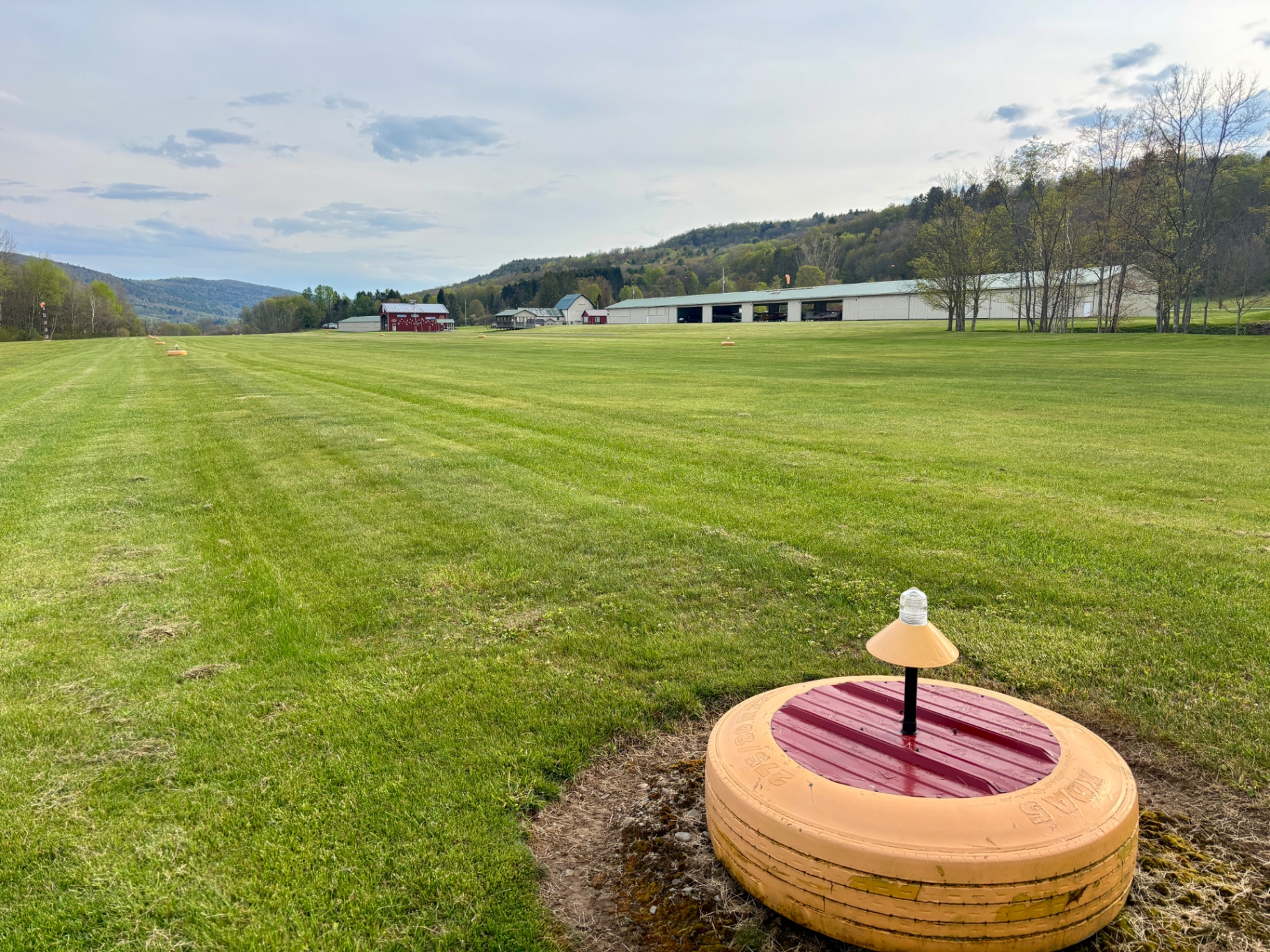 Runway marker with hangars and hills in the distance on a spring day