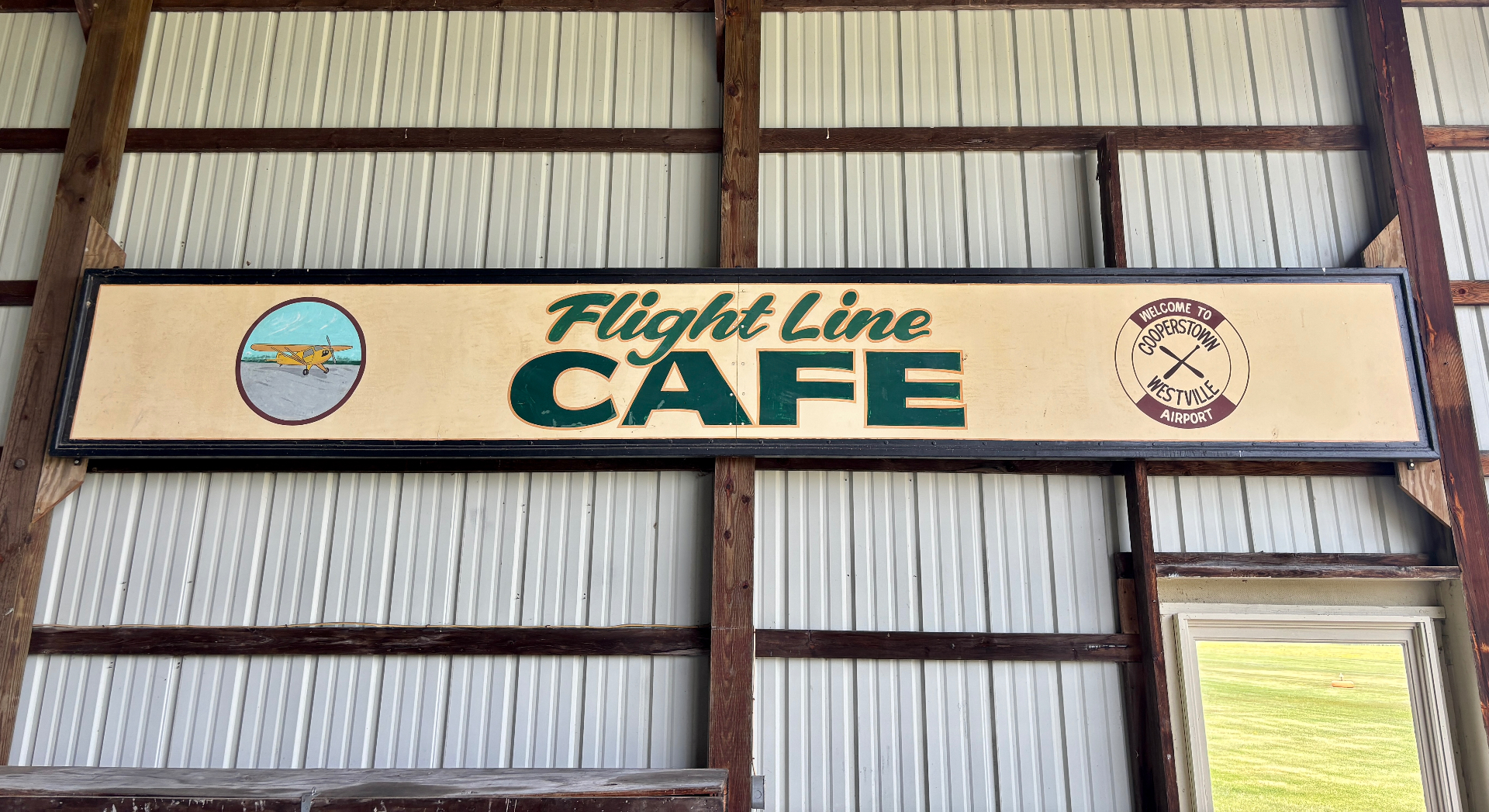 Flight Line Cafe vintage sign inside hangar with Piper Cub artwork