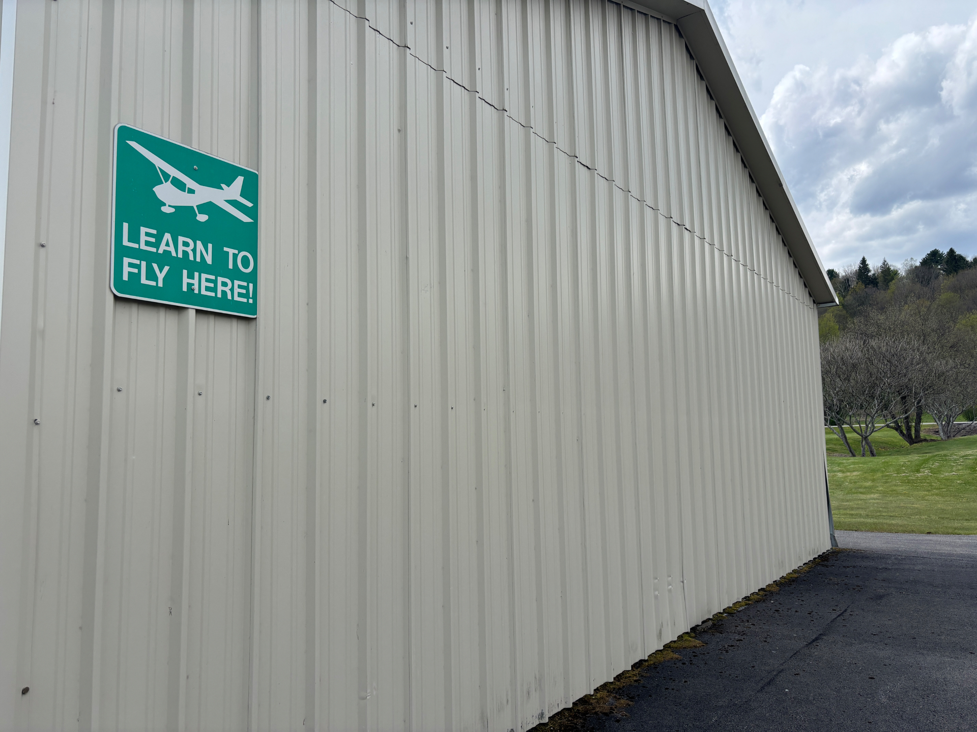 Learn to Fly Here sign on hangar wall