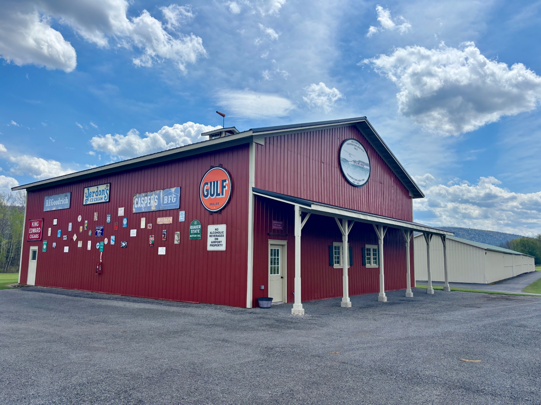Red hangar with vintage signs, Gulf logo, and airport emblem on a sunny day