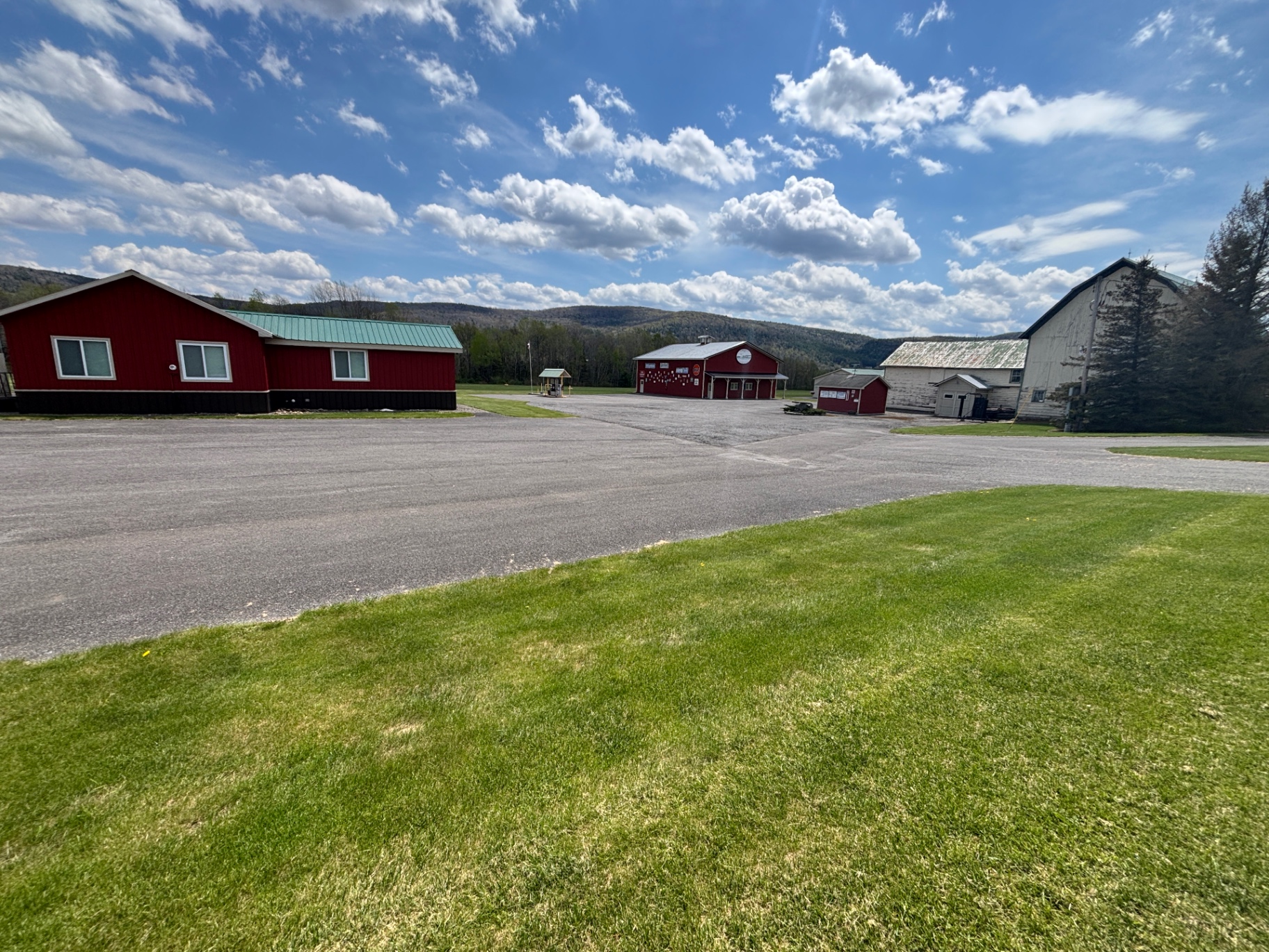 Airport grounds with office, hangars, barn and hills under blue sky