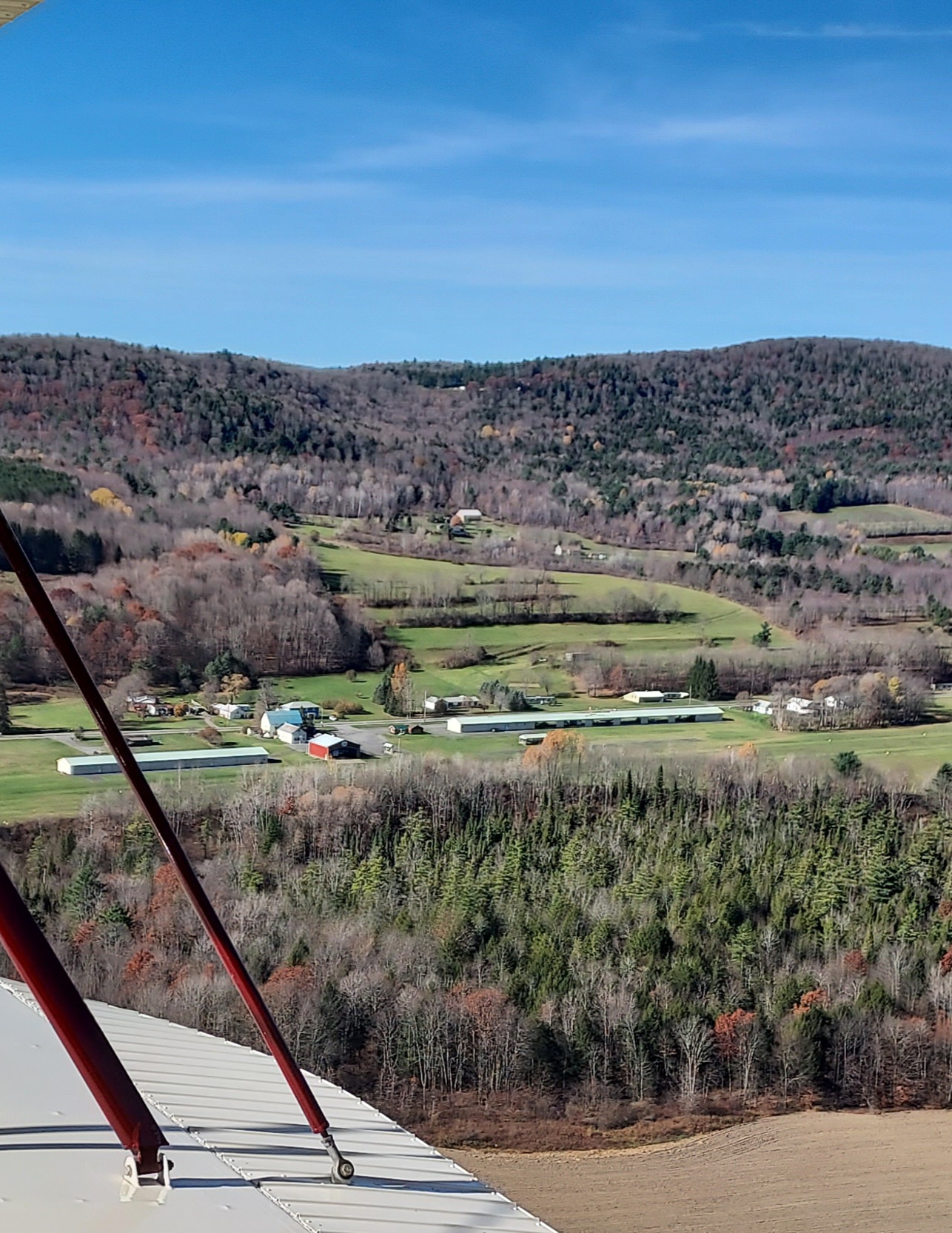 Aerial view from biplane wing over Cooperstown valley in late autumn