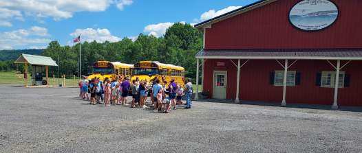 School buses parked at the red hangar with kids visiting on a field trip